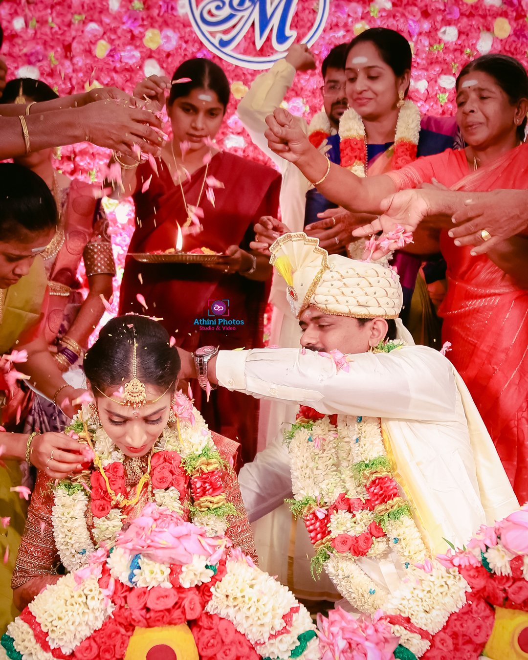 A bride and groom smiling surrounded by guests at their wedding photoshoot.