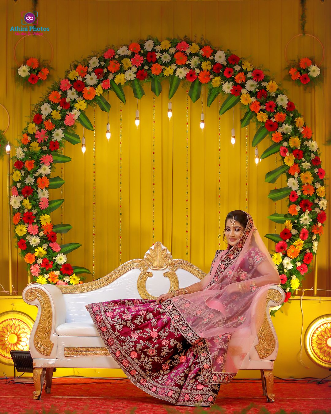 A Muslim bride in a colorful lehenga sitting elegantly on a couch.