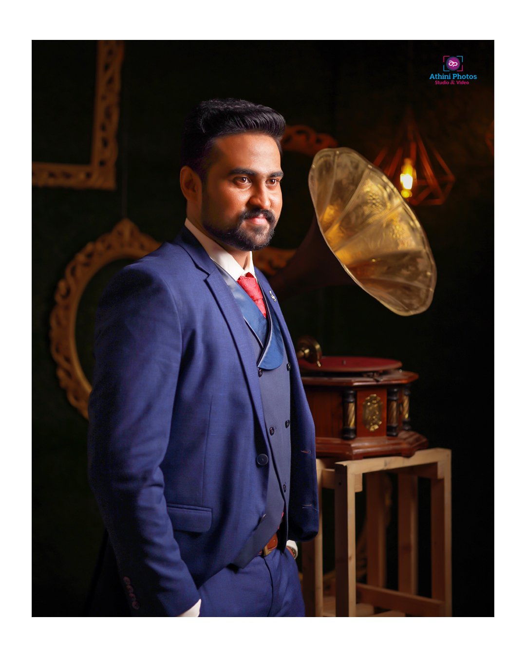 A man in a suit and tie standing next to a gramophone during a wedding photoshoot.
