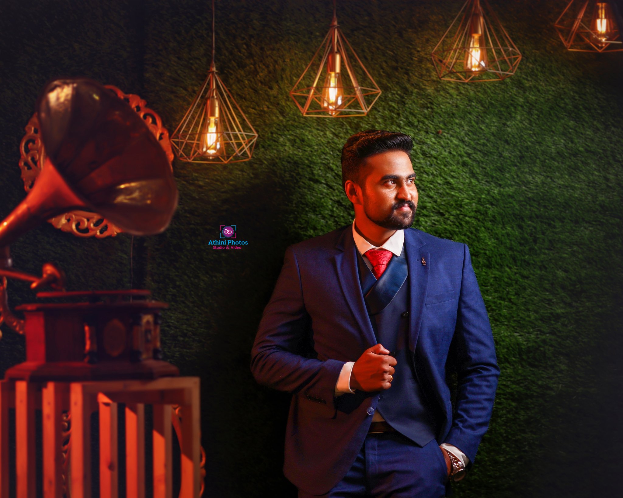 A well-dressed man, suited up and standing next to a gramophone, adding vintage charm to a wedding photoshoot.