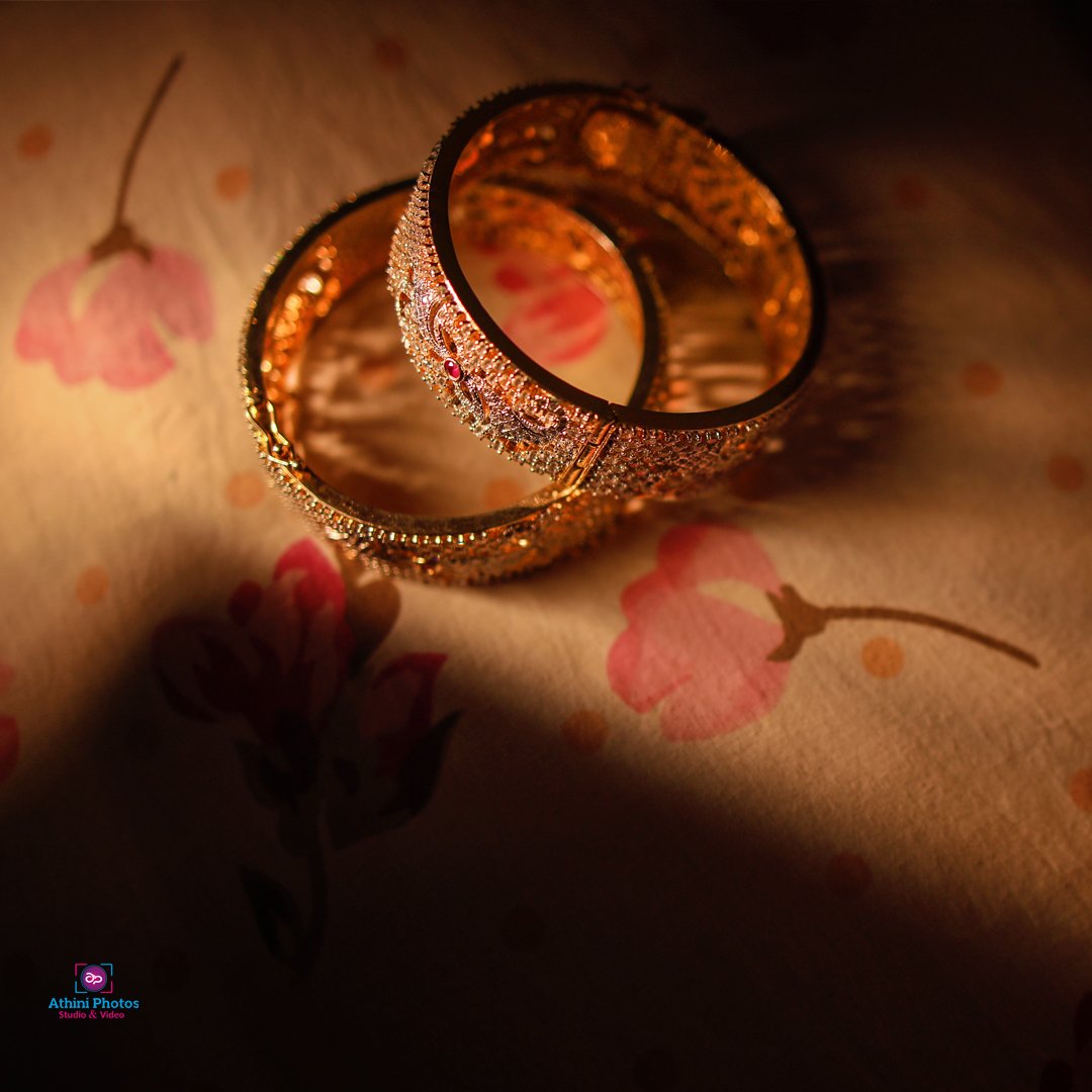 Two gold bangles elegantly placed on a bed, ready to be adorned for a wedding photoshoot.
