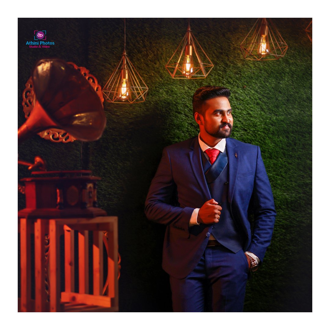 A dapper man in a suit and tie posing next to a gramophone during a wedding photoshoot.